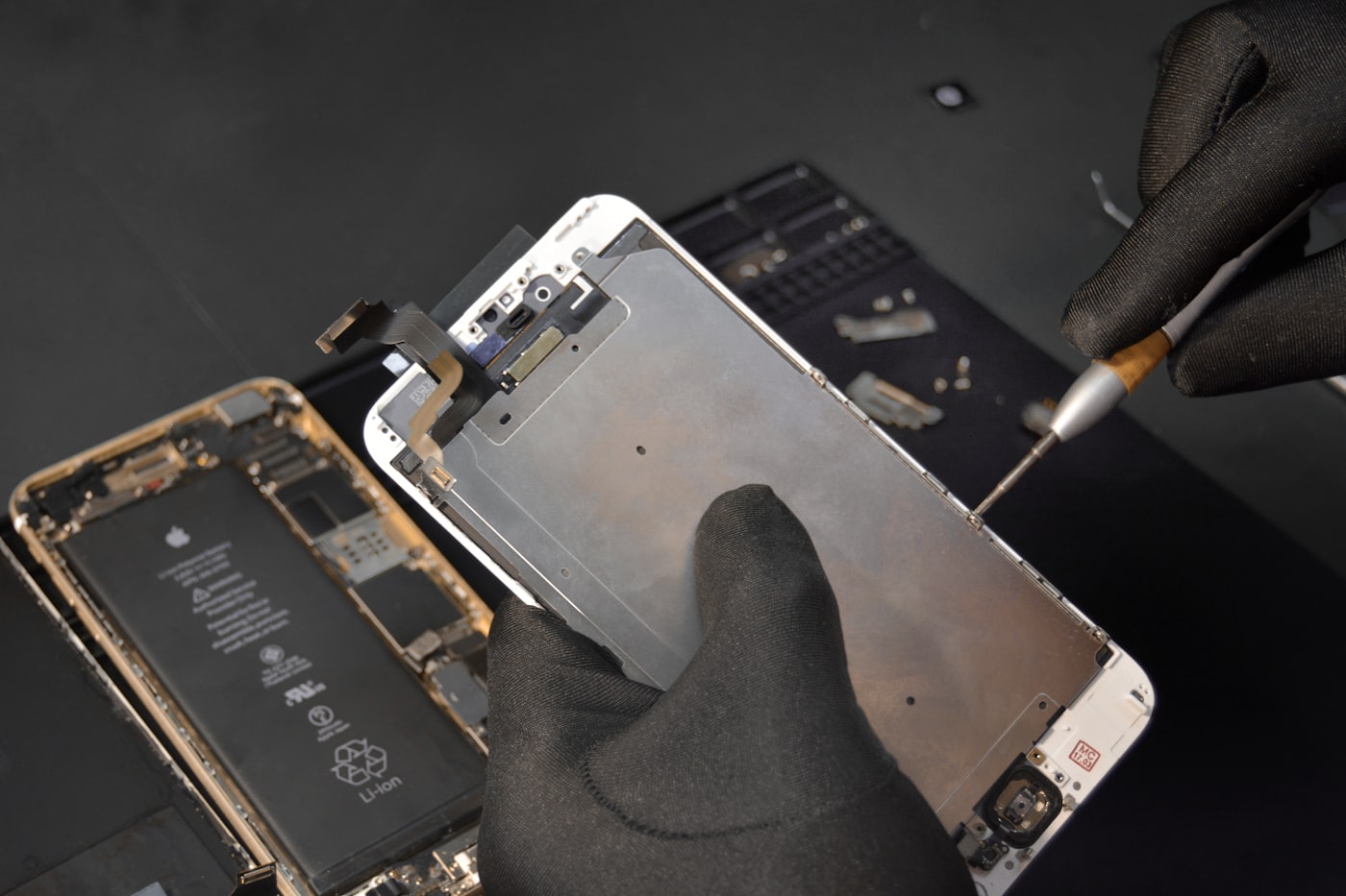 Technicien remplaçant l'écran d'un smartphone avec des gants et un tournevis de précision